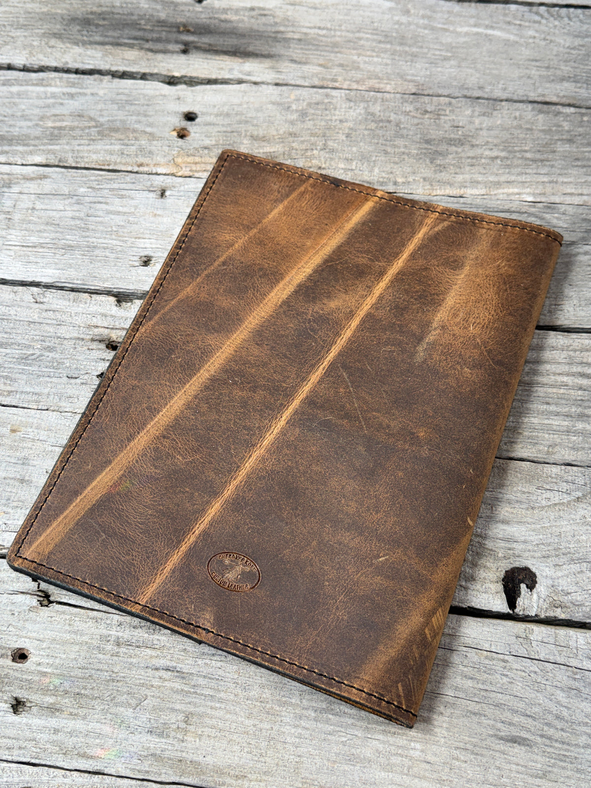 Rustic brown full grain leather composition notebook cover showing dramatic natural range marks
