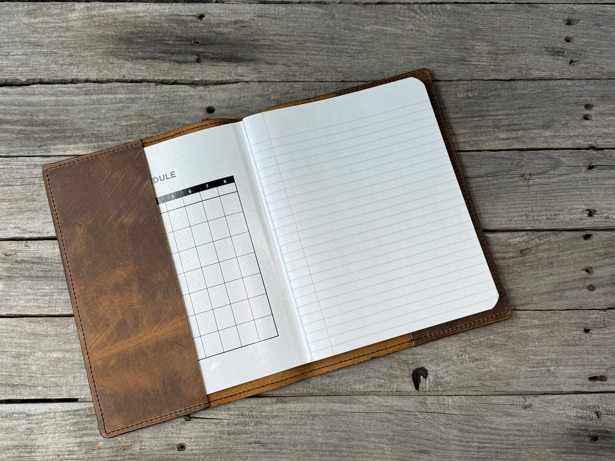 Rustic brown leather composition notebook cover open with refillable wide ruled notebook