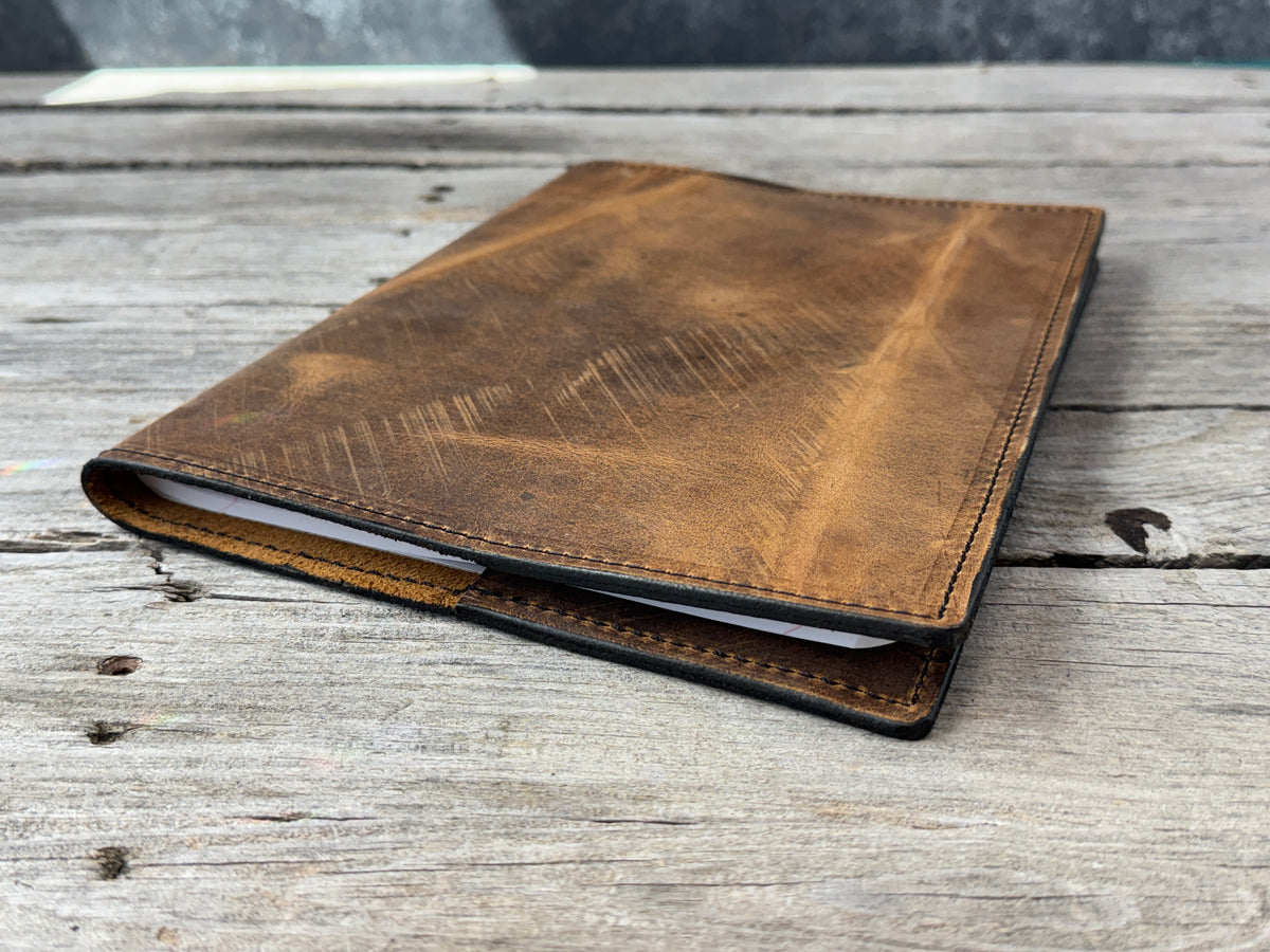 Rustic brown leather composition notebook cover showing natural range marks and finished edges