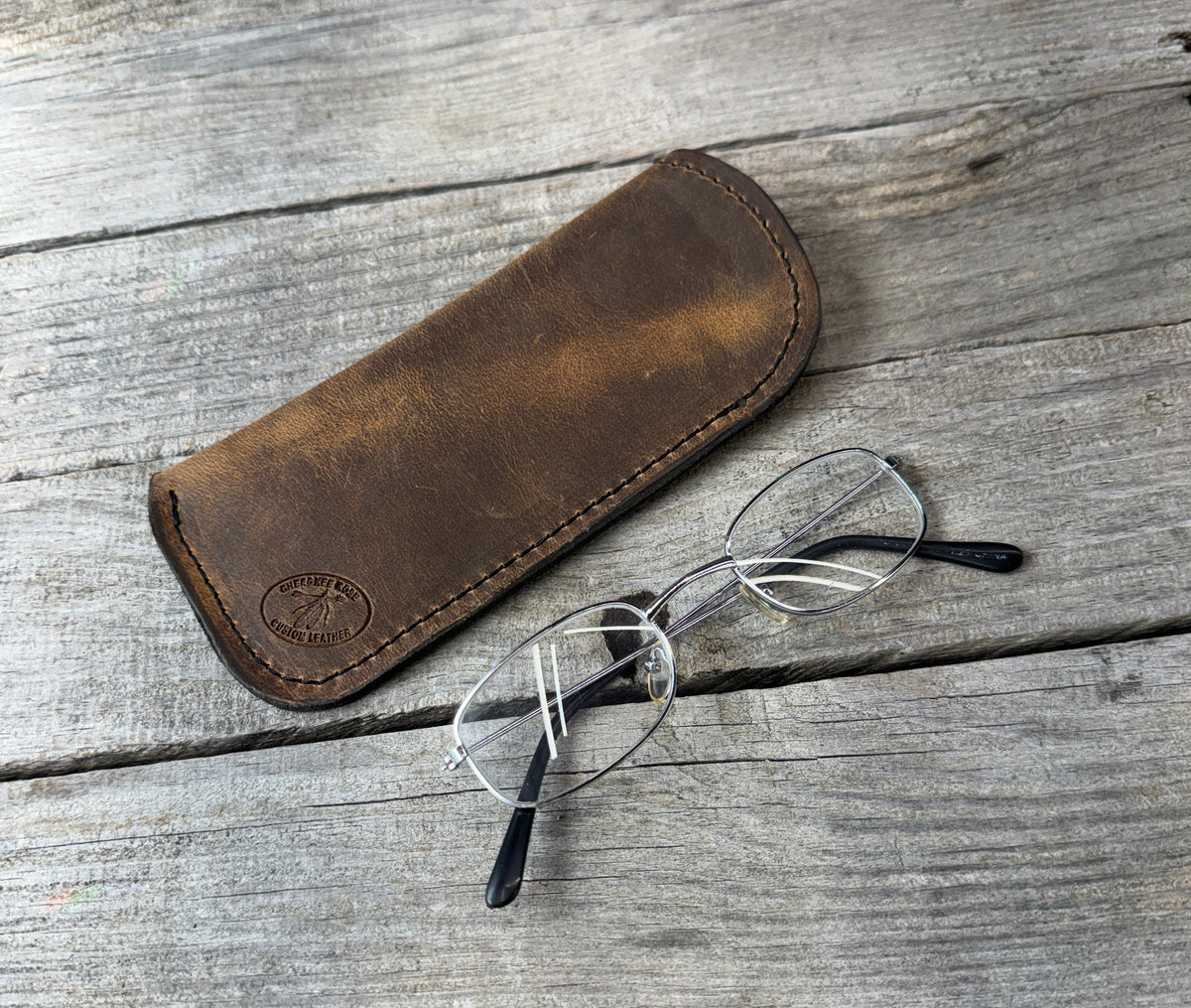Rustic brown leather eyeglass case showing natural leather grain and black stitching