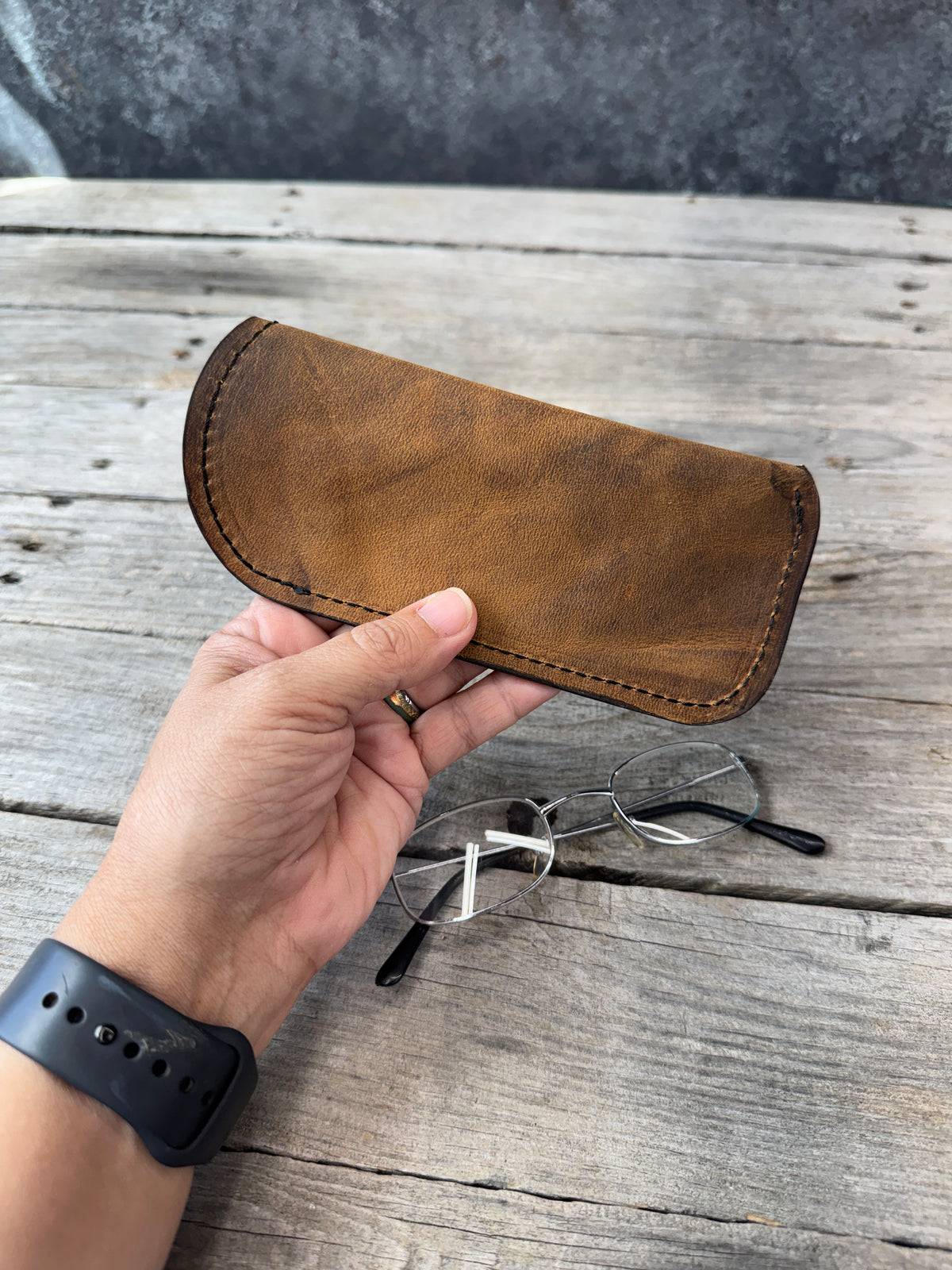 Rustic brown full grain leather eyeglass case held in hand