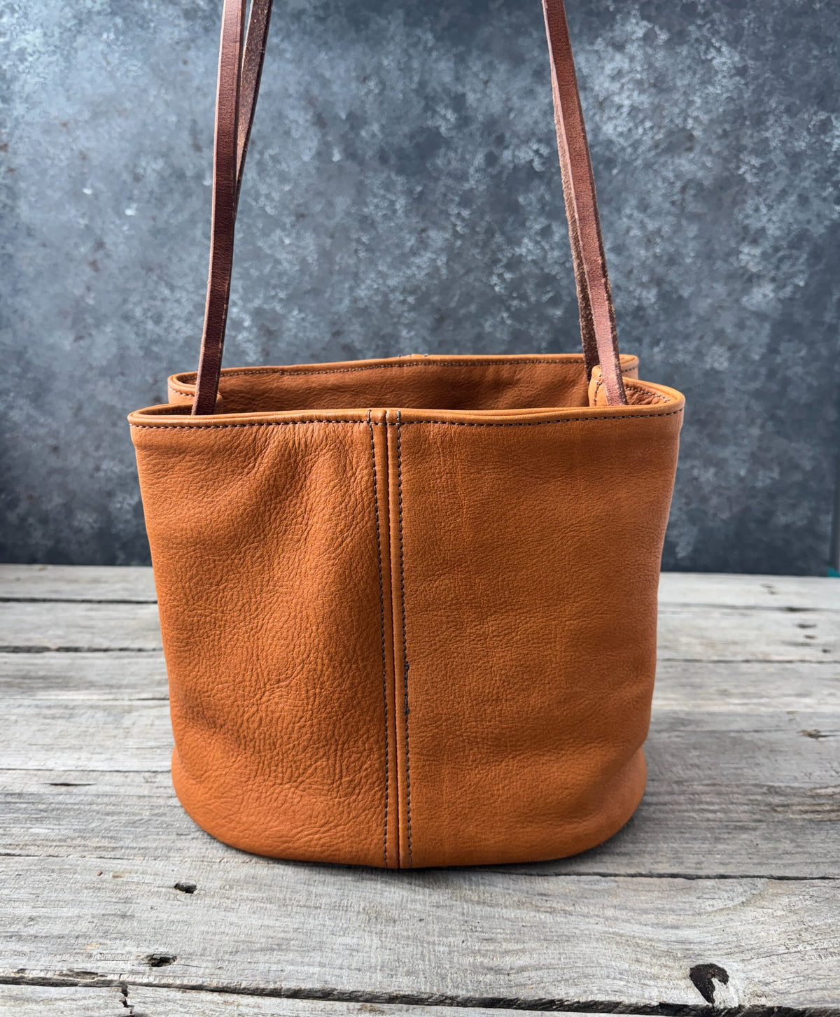 Handmade leather bucket bag showing textured saddle tan leather and stitched panels