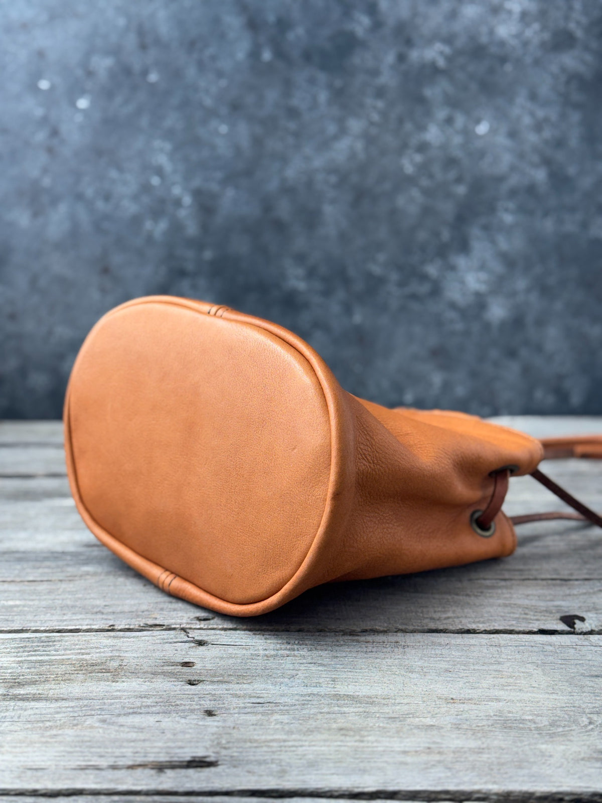 Saddle tan leather bucket purse front view with vertical stitched seam