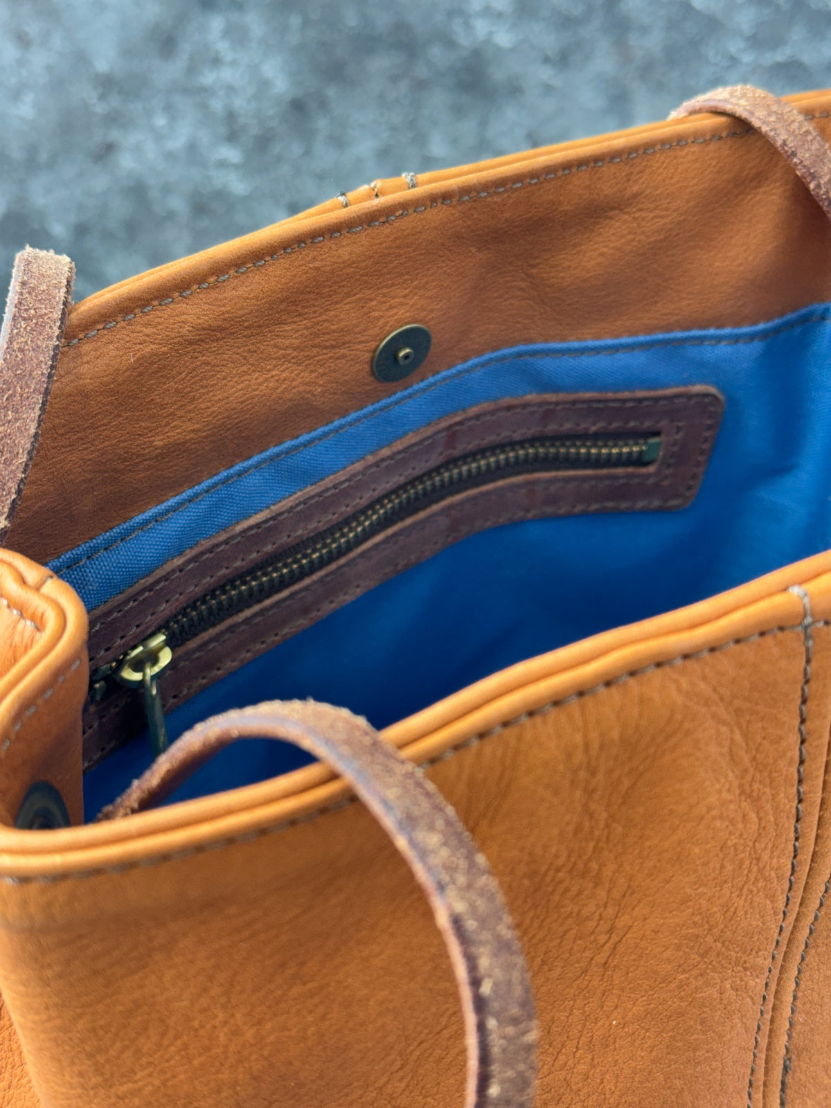 Leather bucket bag interior showing blue lining zippered pocket and magnetic snap