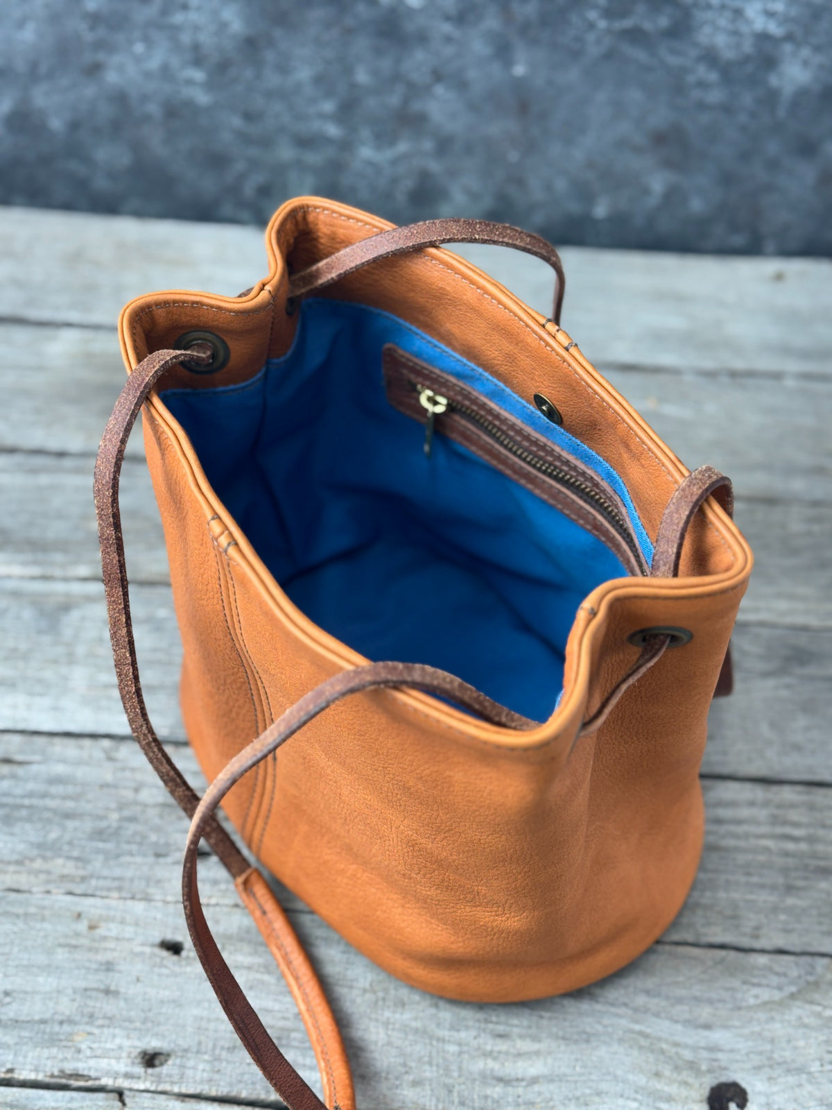 Saddle tan leather bucket purse overhead view of blue lining and interior zip pocket