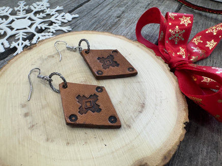 Small diamond-shaped hand-stamped leather earrings with Southwestern sun design and sterling silver hooks, handmade by Cherokee Rose Custom Leather in Texas