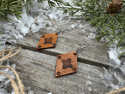 Small diamond-shaped hand-stamped leather earrings with Southwestern sun design and sterling silver hooks, handmade by Cherokee Rose Custom Leather in Texas