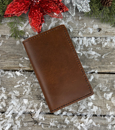 Handmade leather Field Notes cover in smooth oil-tanned brown leather with black stitching, crafted by Cherokee Rose Custom Leather in East Texas.