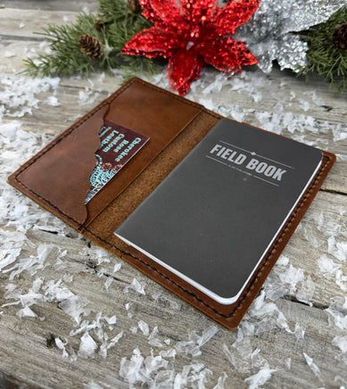 Handmade leather Field Notes cover in smooth oil-tanned brown leather with black stitching, crafted by Cherokee Rose Custom Leather in East Texas.