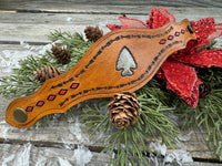 Hand-tooled leather cuff bracelet with arrowhead centerpiece, red diamond accents, and antique brass snaps, handmade by Cherokee Rose Custom Leather in Texas.