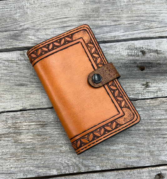 Brown leather wallet with intricate designs on a wooden surface
