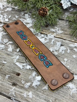 Wide hand-carved leather cuff bracelet with turquoise arrow and yellow tribal design, antique copper snaps, and yellow suede lining, handmade by Cherokee Rose Custom Leather.