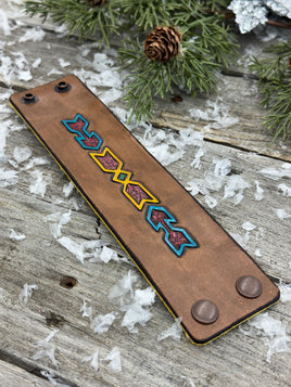 Wide hand-carved leather cuff bracelet with turquoise arrow and yellow tribal design, antique copper snaps, and yellow suede lining, handmade by Cherokee Rose Custom Leather.