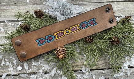 Wide hand-carved leather cuff bracelet with turquoise arrow and yellow tribal design, antique copper snaps, and yellow suede lining, handmade by Cherokee Rose Custom Leather.