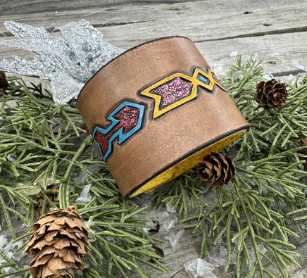 Wide hand-carved leather cuff bracelet with turquoise arrow and yellow tribal design, antique copper snaps, and yellow suede lining, handmade by Cherokee Rose Custom Leather.