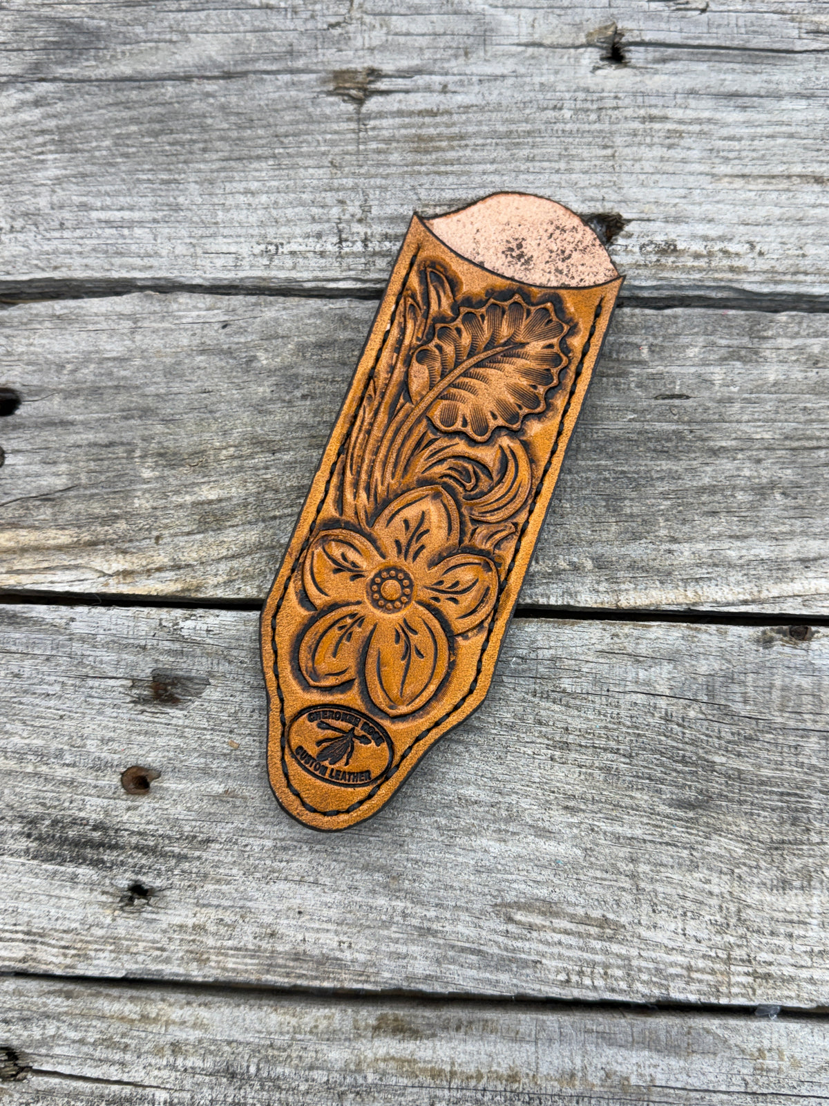 Decorative leather tool with floral patterns on a wooden surface