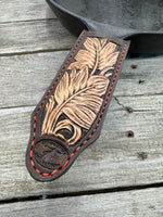 Hand tooled leather cast iron skillet handle cover in chocolate brown with carved leaf design and red stitching, handmade by Cherokee Rose Custom Leather in East Texas.