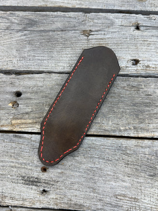 Hand tooled leather cast iron skillet handle cover in chocolate brown with carved leaf design and red stitching, handmade by Cherokee Rose Custom Leather in East Texas.