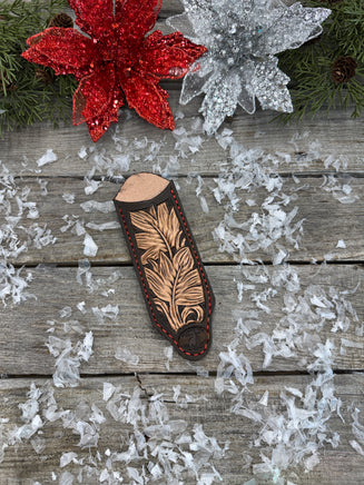 Hand tooled leather cast iron skillet handle cover in chocolate brown with carved leaf design and red stitching, handmade by Cherokee Rose Custom Leather in East Texas.