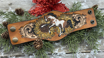 Wide hand-painted leather cuff bracelet with wild paint pony, sunflowers, and antique brass snaps, handmade by Cherokee Rose Custom Leather in East Texas.