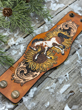 Wide hand-painted leather cuff bracelet with wild paint pony, sunflowers, and antique brass snaps, handmade by Cherokee Rose Custom Leather in East Texas.