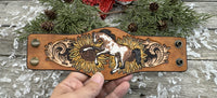 Wide hand-painted leather cuff bracelet with wild paint pony, sunflowers, and antique brass snaps, handmade by Cherokee Rose Custom Leather in East Texas.