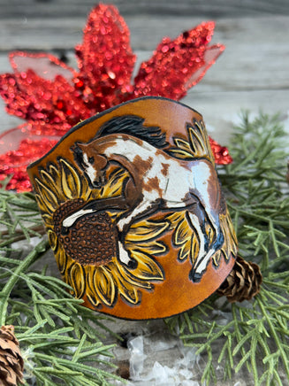 Wide hand-painted leather cuff bracelet with wild paint pony, sunflowers, and antique brass snaps, handmade by Cherokee Rose Custom Leather in East Texas.